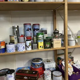 Stellage met diverse blikken, potjes en decoratieve voorraaddozen, waaronder blauwe porseleinen potten en gele blikken