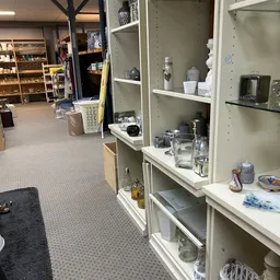 Witte stellingkasten met huishoudelijke artikelen en serviesgoed in een kringloopwinkel