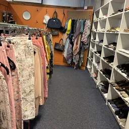 Kledingrekken en schoenenrekken in kringloopwinkel met tweedehands kleding en accessoires