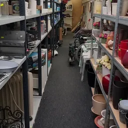 Winkelpad met stellingen vol huishoudelijke artikelen, bloemen en decoratie aan beide zijden