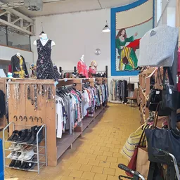 Winkelvloer met kledingrekken, stellingen met tweedehands kleding en accessoires, gele tegelvloer