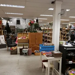 Winkelvloer van kringloopwinkel met boekenrekken, huishoudelijke artikelen, decoraties en meubels verspreid over het winkelge