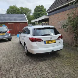 Parkeerplaats met twee auto's naast een bakstenen garage met groene beplanting