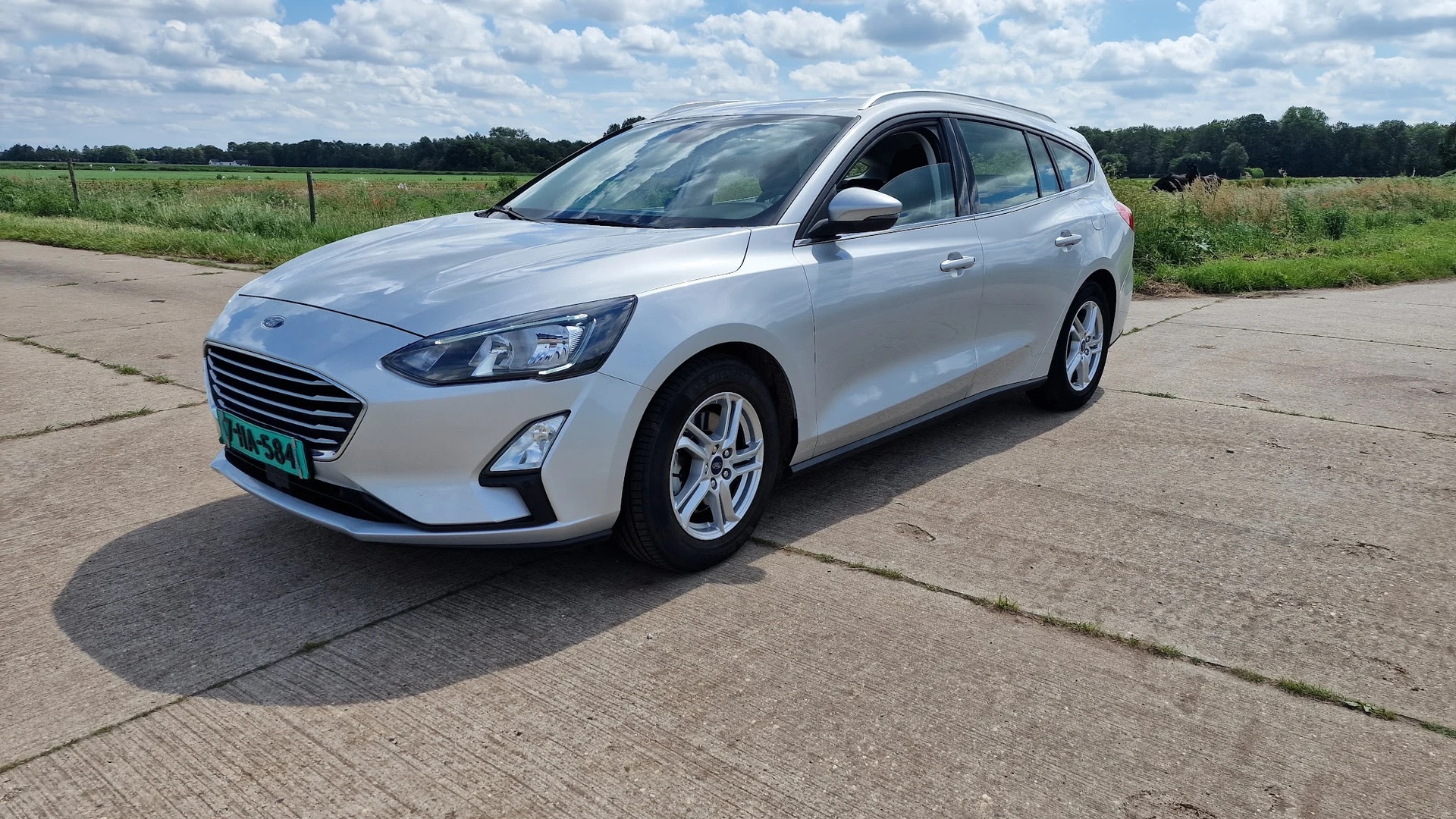 Witte Ford Focus stationwagen op parkeerplaats, volzijde aanzicht
