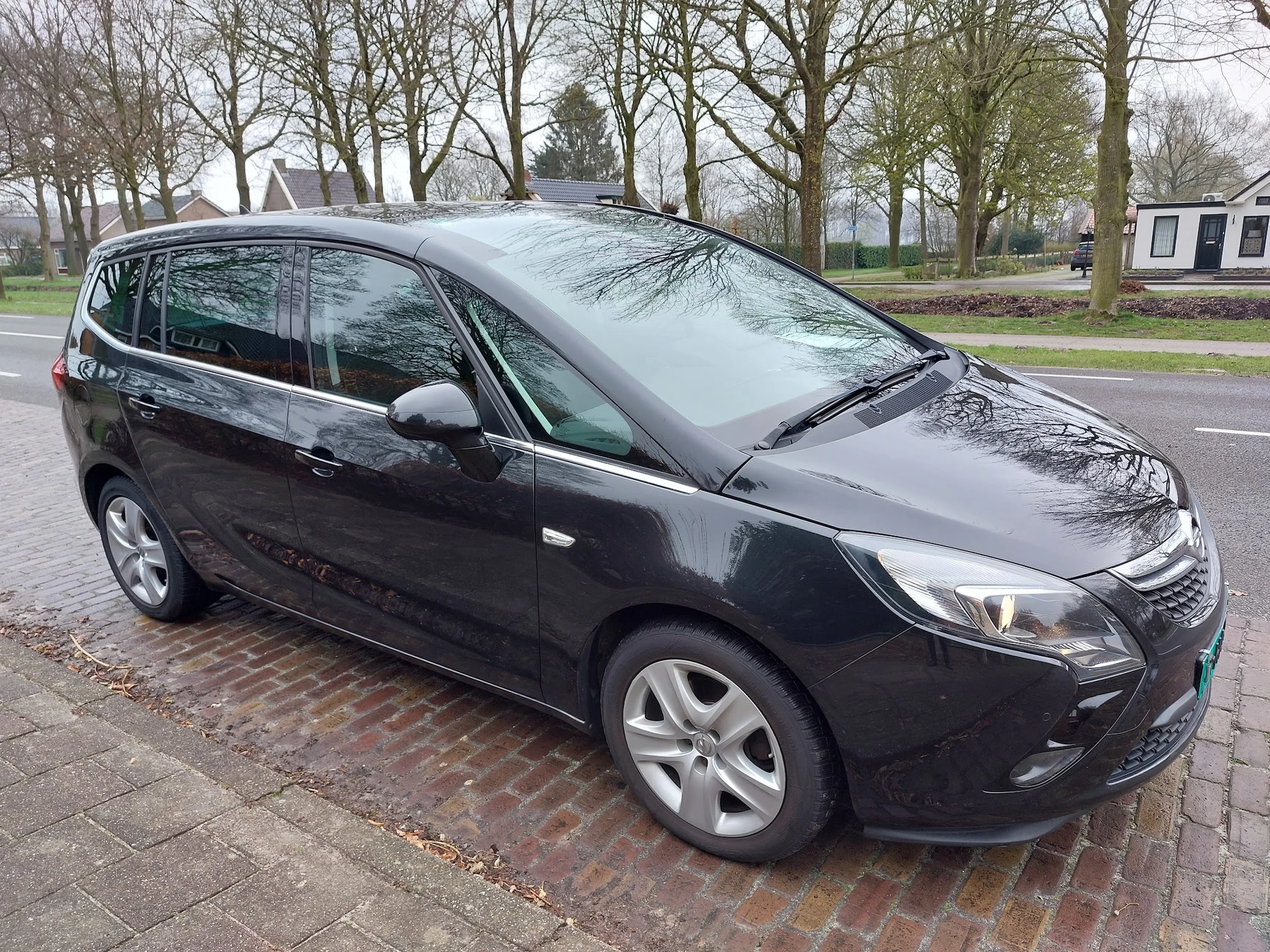 Zwarte Opel Zafira MPV geparkeerd op straat met bomen op achtergrond