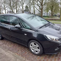 Zwarte Opel Zafira MPV geparkeerd op straat met bomen op achtergrond