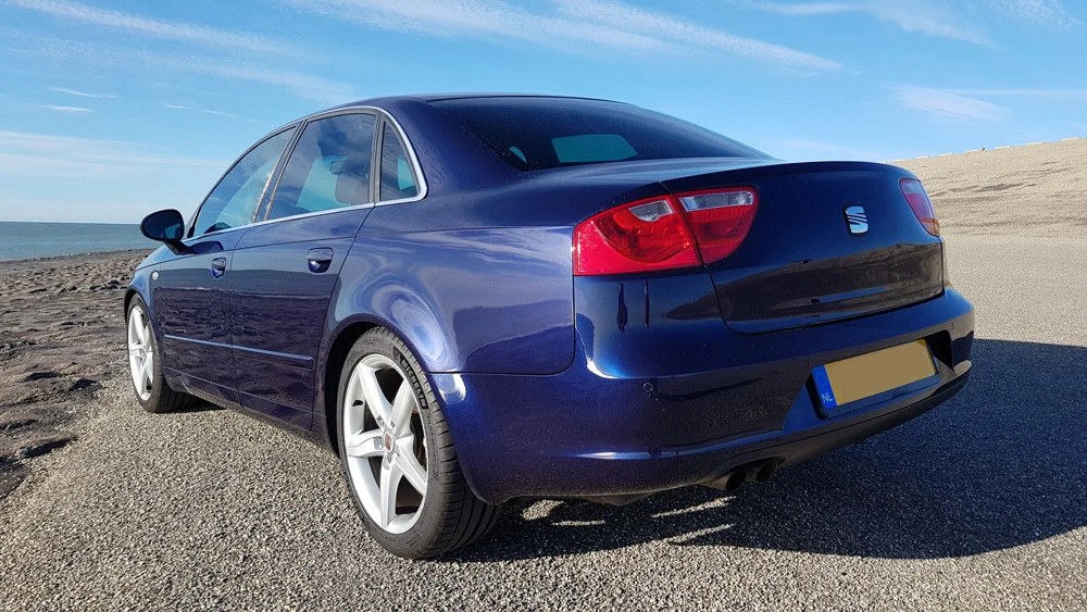 Blauwe Seat sedan geparkeerd op asfalt, zijkant met achterlichten zichtbaar