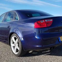 Blauwe Seat sedan geparkeerd op asfalt, zijkant met achterlichten zichtbaar