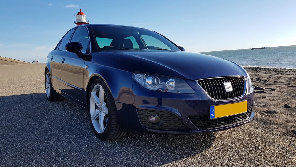Blauwe SEAT Ibiza met een rood-wit zwaailicht op het dak, geparkeerd op een parkeerplaats bij het strand