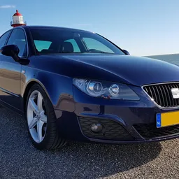 Blauwe SEAT Ibiza met een rood-wit zwaailicht op het dak, geparkeerd op een parkeerplaats bij het strand