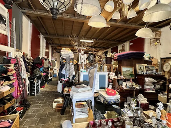 Overzicht van de winkelvloer met verschillende afdelingen, stellingen met kleding, meubels, huishoudartikelen en decoratie ve