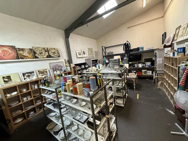 Winkelinterieur met stellingen, vitrines en uiteenlopende spullen zoals servies, kunstwerken en decoratieve items