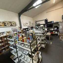 Winkelinterieur met stellingen, vitrines en uiteenlopende spullen zoals servies, kunstwerken en decoratieve items