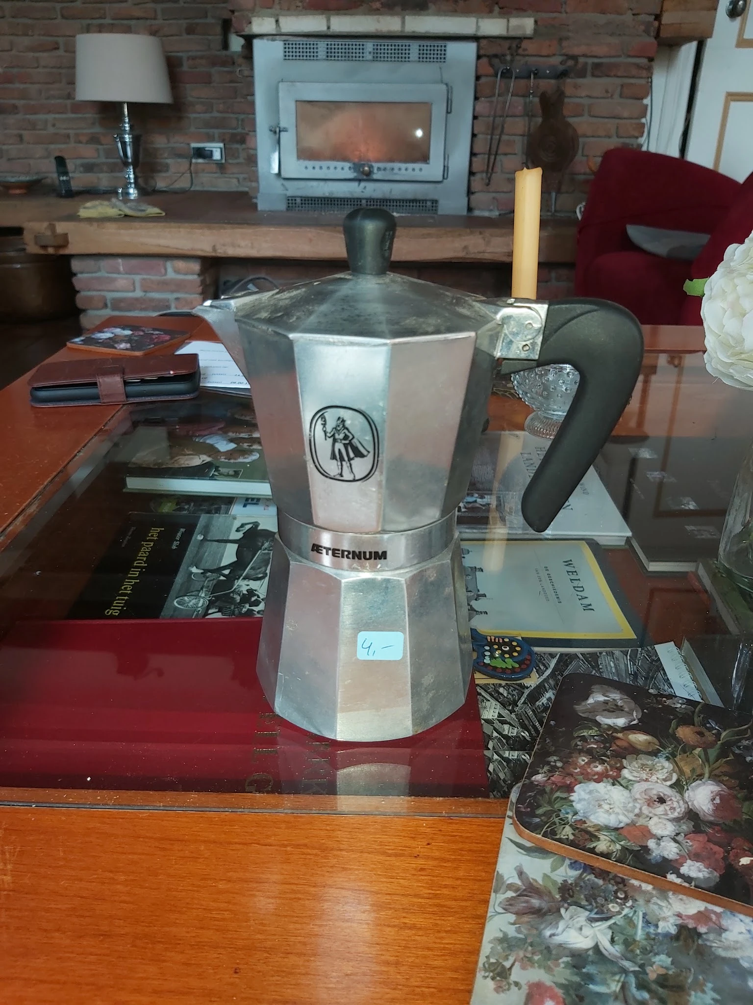 Moka pot espressomachine met wit/grijs design en zwarte handgreep op houten tafel