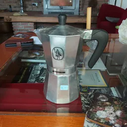 Moka pot espressomachine met wit/grijs design en zwarte handgreep op houten tafel