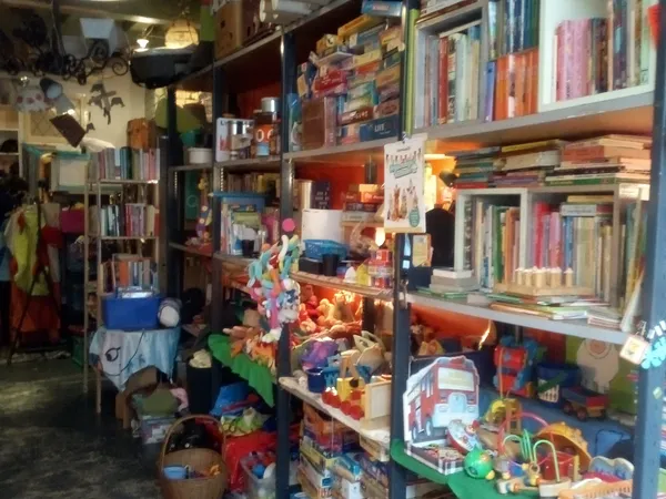 Winkelinterieur met boekenkasten, speelgoed en diverse spullen op stellingen en in bakken