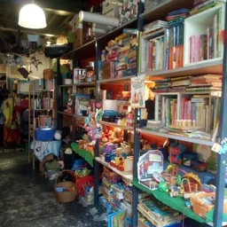Winkelinterieur met boekenkasten, speelgoed en diverse spullen op stellingen en in bakken