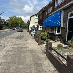 Voorgevel van kringloopwinkel aan straat met blauwe luifel en ingang