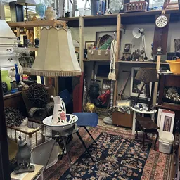Binnenaanzicht van kringloopwinkel met meubels, lampen, decoratie en verschillende spullen verspreid door de ruimte