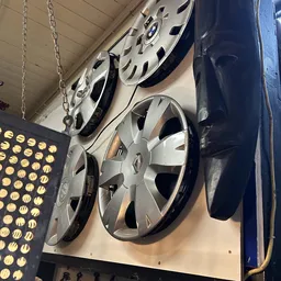 Verschillende autowielen en wieldoppen uitgestald aan het plafond en tegen de muur