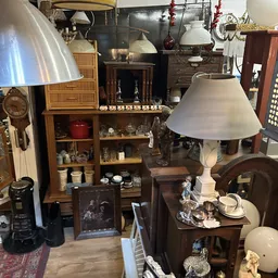 Uitstalling van vintage meubels en decoratieve voorwerpen: houten kasten, lampen, kandelaars, servies en overige brocante-art