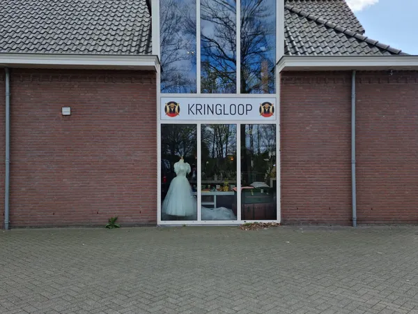 Voorgevel van kringloopwinkel met rode bakstenen muren, witte kozijnen en duidelijk zichtbare winzelnaam KRINGLOOP