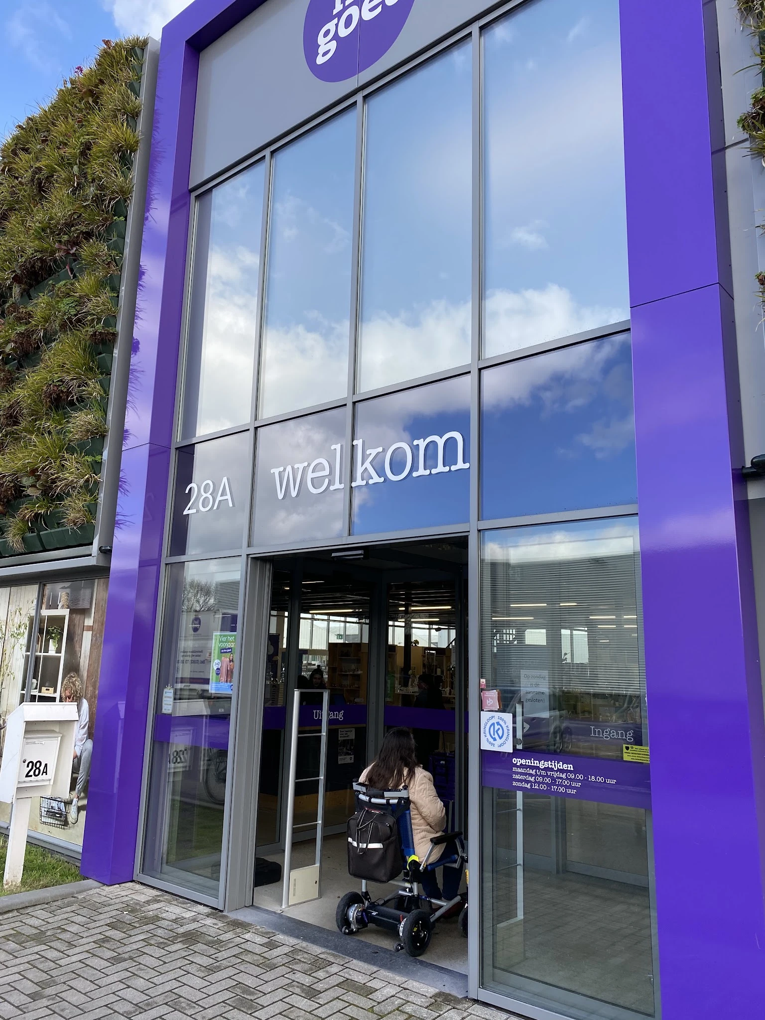 Winkelgevel met paarse zijkanten, glazen deuren en ramen, adres 28A met 'wellkom' tekst