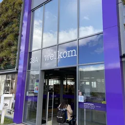 Winkelgevel met paarse zijkanten, glazen deuren en ramen, adres 28A met 'wellkom' tekst