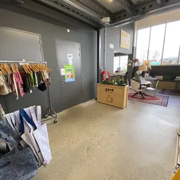 Winkelinterieur met kledingrek, houten plantenbak en winkelruimte met daglicht van buiten