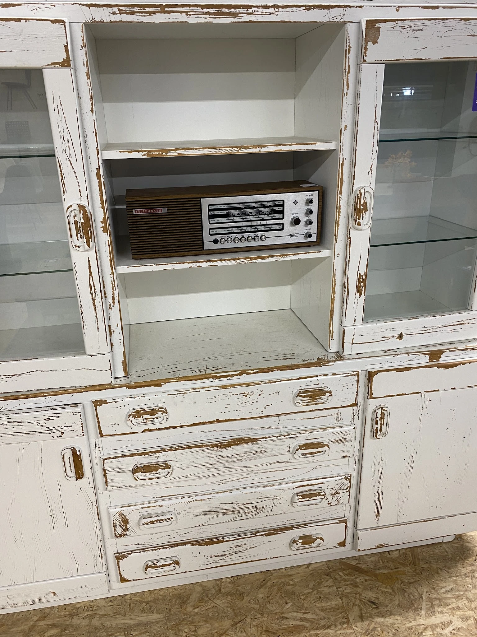Vintage kastje met glasedeuren en lades met daarin een oude radio-tuner