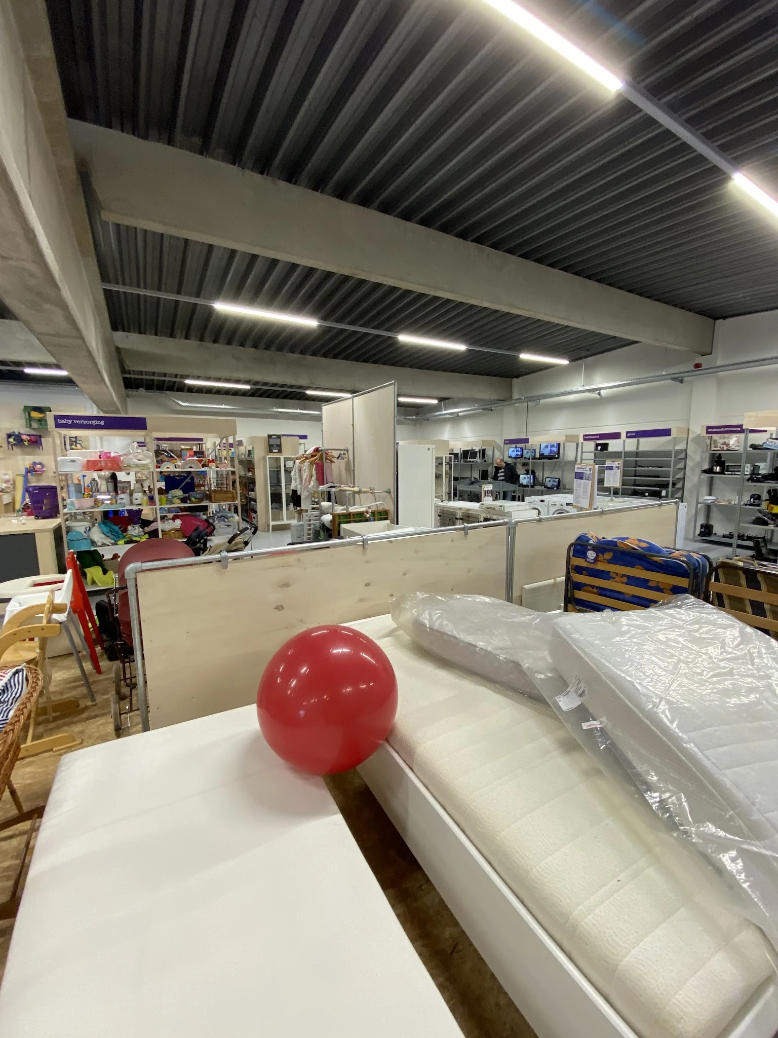 Winkelvloer met stellingen, toonbanken en uiteenlopende artikelen in een kringloopwinkel