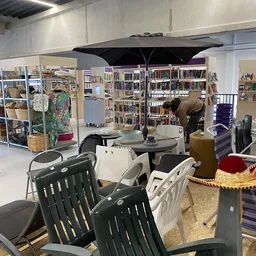 Winkelvloer met zithoeken, boekenkasten en diverse tweedehands artikelen onder zwarte parasol
