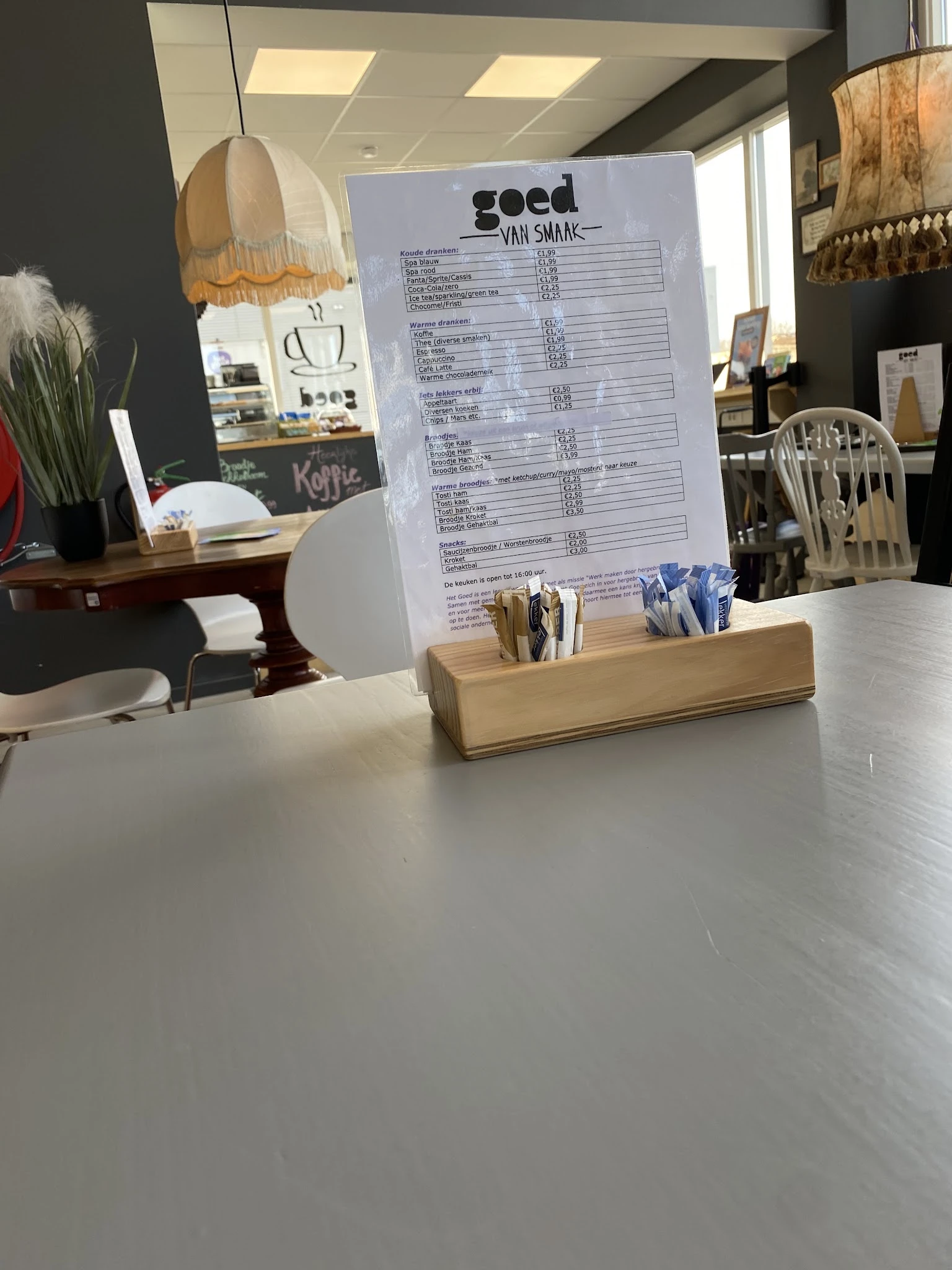 Menukaart of prijslijst achter glas op een houten standaard met servetten op een toonbank
