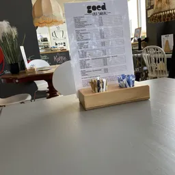 Menukaart of prijslijst achter glas op een houten standaard met servetten op een toonbank