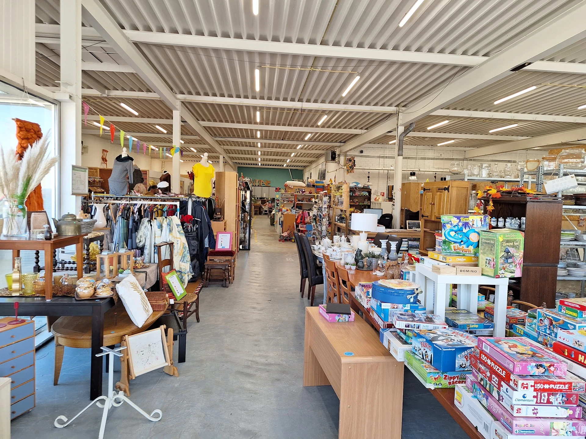 Overzicht van de winkelvloer met verschillende afdelingen: kleding, boeken, huishoudspullen en ander vintage- en tweedehandsa