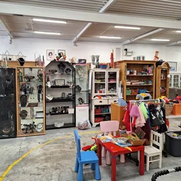 Winkelvloer met speelgoed, kleding en meubels; zicht op stellingen en afdelingen