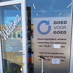 Openingstijden en inlevermogelijkheden van kringloopwinkel Goed voor Goed op een wit bord aan de winkelpui