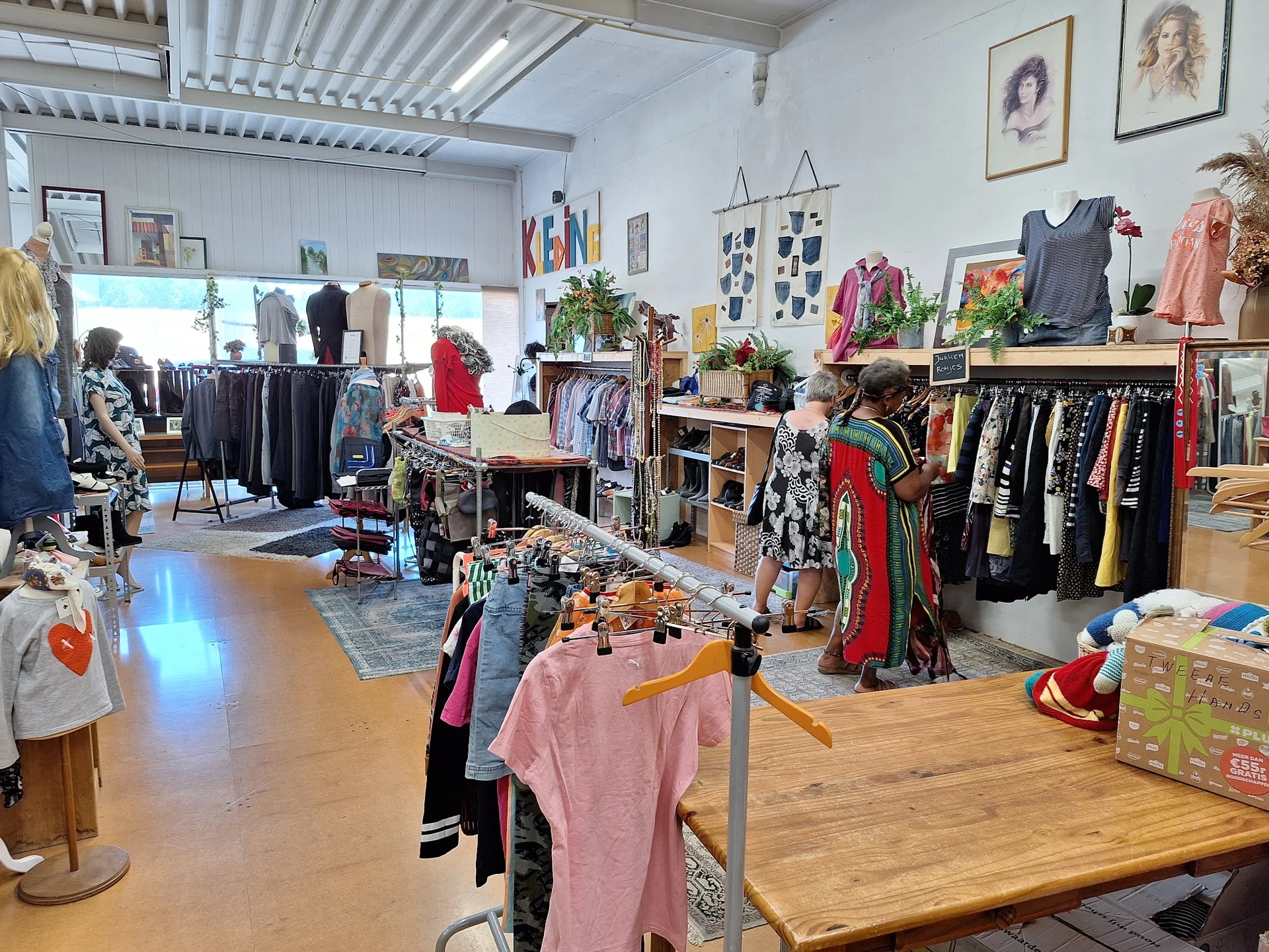 Overzicht van de winkelvloer met kleding op rekken, tafels met spullen en diverse artikelen uitgestald