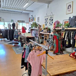 Overzicht van de winkelvloer met kleding op rekken, tafels met spullen en diverse artikelen uitgestald