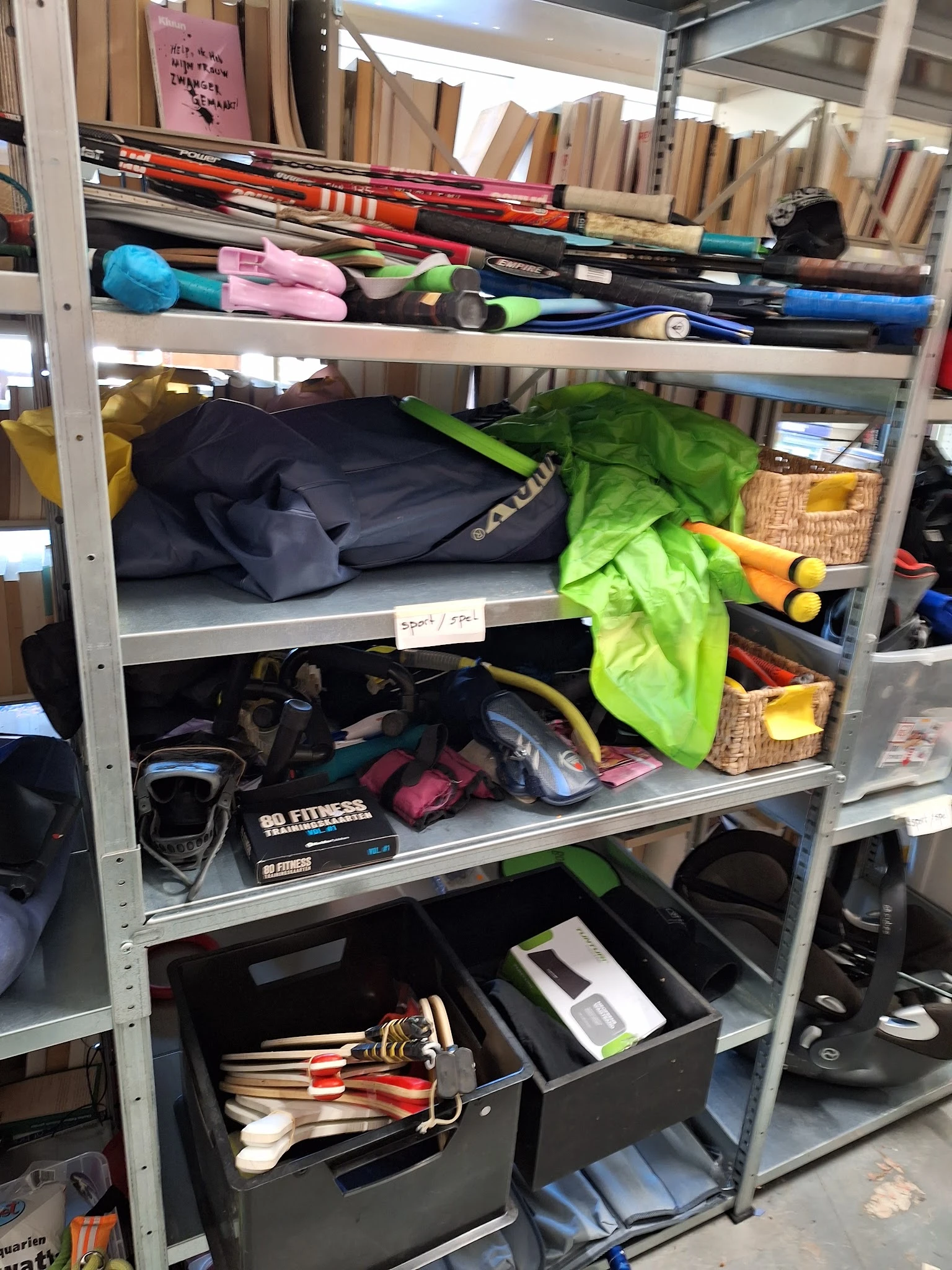 Stellingen met tweedehands sportartikelen en tassen in een kringloopwinkel