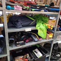 Stellingen met tweedehands sportartikelen en tassen in een kringloopwinkel