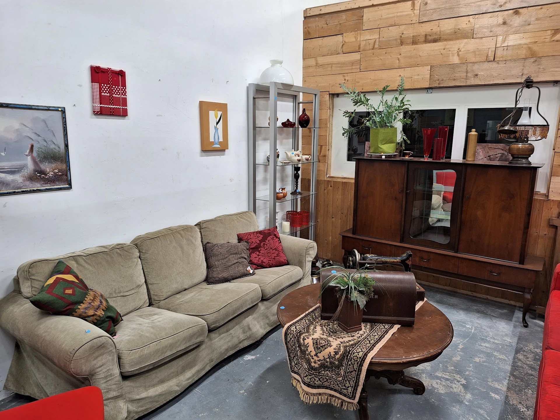 Woonkamer met grijsbeige bank, houten TV-meubel, salontafel en decoratieve elementen in kringloopwinkel