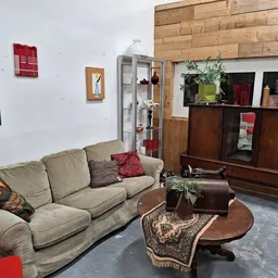Woonkamer met grijsbeige bank, houten TV-meubel, salontafel en decoratieve elementen in kringloopwinkel