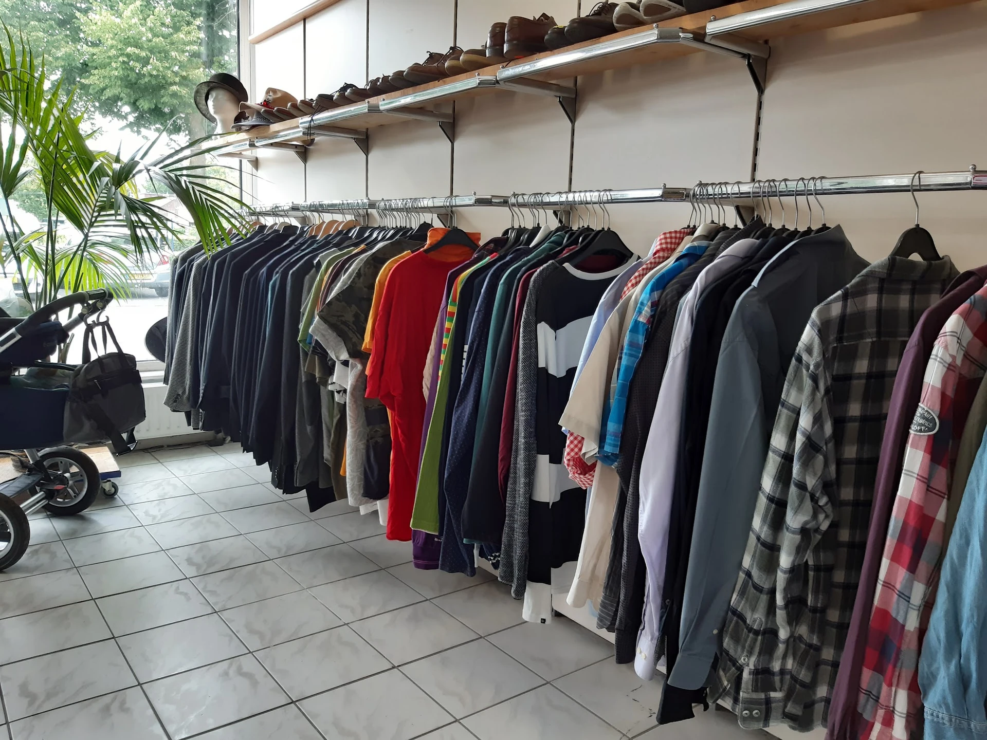Rekken met tweedehands kleding in verschillende kleuren en stijlen, waaronder geruit patroon en rode stuks