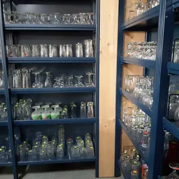 Glazen kasten met veel verschillende glazen, kannen en serviesgoed netjes uitgestald