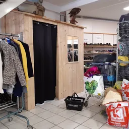 Winkelvloer met kledingrekken, houten kaststructuur met paskamer, schoenenplank en dozen met spullen