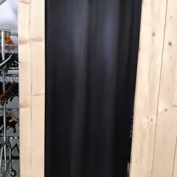 Zwart gordijn of textiel uitgestald tegen houten wand in winkel