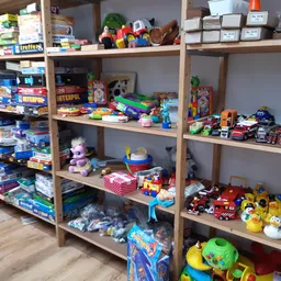 Stellingen met speelgoed, plastic speelfiguren, auto's, poppen en diverse kinderspeelgoed in de kringloopwinkel