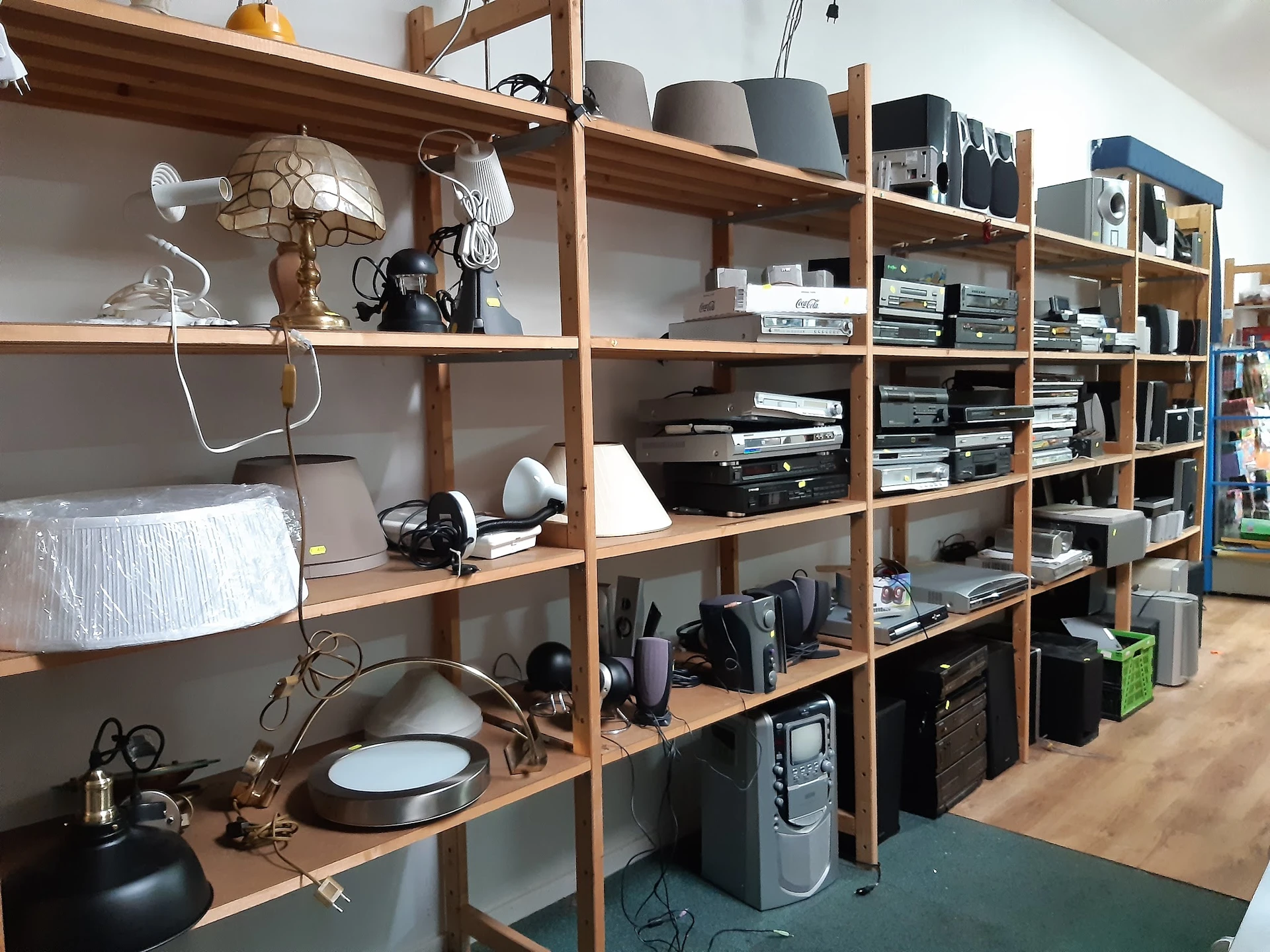 Houten stellingkast met elektronicaartikelen, speakers en apparatuur in een kringloopwinkel