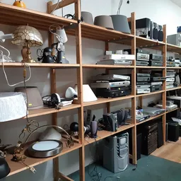 Houten stellingkast met elektronicaartikelen, speakers en apparatuur in een kringloopwinkel